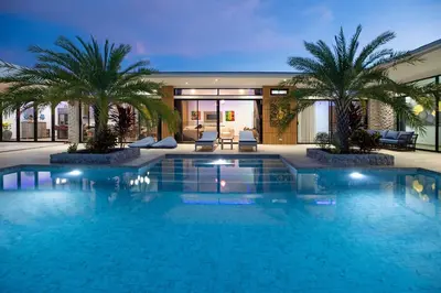 a swimming pool with palm trees in a building at Pattana Sun Villa - Modern 4 Bedrooms Villa with Pool in Ban Saiyuan (1)
