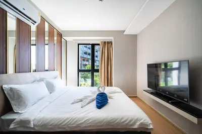 a bedroom with a white bed with a tv and a bed sidx sidx at Surin Beach Serviced 3 Bedroom Sea View Apart-ment Comprehensive Facilities Resort Pool Gym Guest Choice in Surin Beach