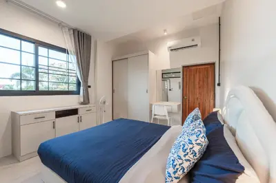a bedroom with a blue and white bed and a kitchen at Areca Holiday Villa 3, Naiharn Beach in Rawai Beach