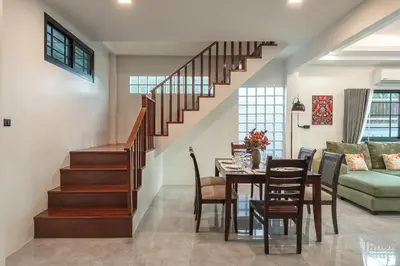 a dining room and living room with a staircase at Areca Holiday Villa 3, Naiharn Beach in Rawai Beach
