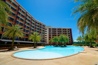 a swimming pool in front of a building with palm trees at Nature View Residence in Ban Mai Salae