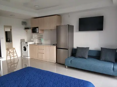 a living room with a blue couch and a kitchen at Nature View Residence in Ban Mai Salae
