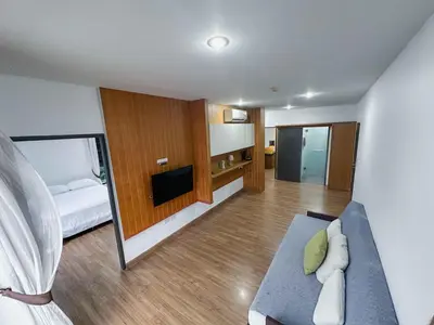 a room with a couch and a bed and a television at Beachside Bliss 2- Bed HM612 in Phuket Town