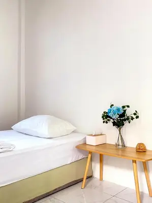 a bedroom with a bed and a table with a vase of flowers at Friends Retreat - Phuket Airport in Ban Bo Han