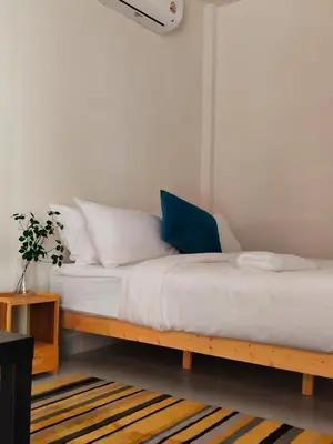 a bed with white sheets and a blue pillow at Friends Retreat - Phuket Airport in Ban Bo Han