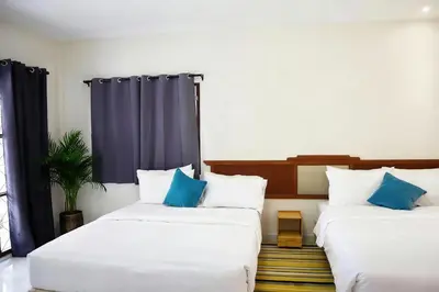two beds in a room with blue and white pillows at Friends Retreat - Phuket Airport in Ban Bo Han