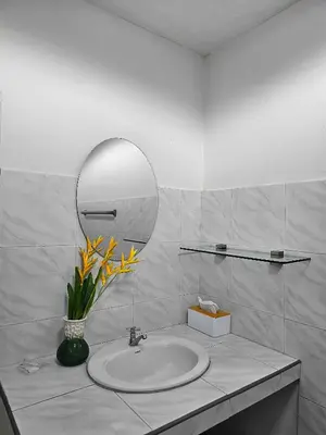 a bathroom with a sink with a mirror and flowers at Friends Retreat - Phuket Airport in Ban Bo Han