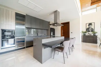 a kitchen with a large counter and chairs in it at Luxury 4BR Pool Villa Botanica Bangtao Beach in Ban Thalat Choeng Thale