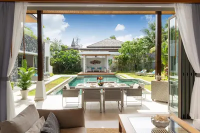 an open patio with a table and chairs and a pool at Luxury 4BR Pool Villa Botanica Bangtao Beach in Ban Thalat Choeng Thale