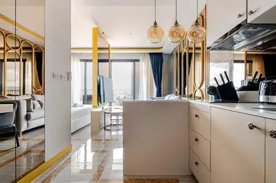 a kitchen with white cabinets and a living room at Bellevue by Villacarte in Laguna Phuket