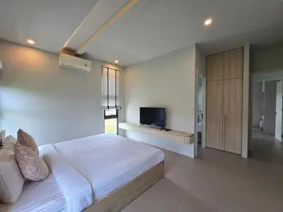 a bedroom with a white bed and a television at Bangtao Family 3 Bedroom Villa in Ban Pak Lak