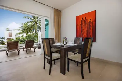 a dining room with a table with chairs and a painting at Tropical Serenity - Elegant 1 Bedroom with Pool in Ban Saiyuan (1)