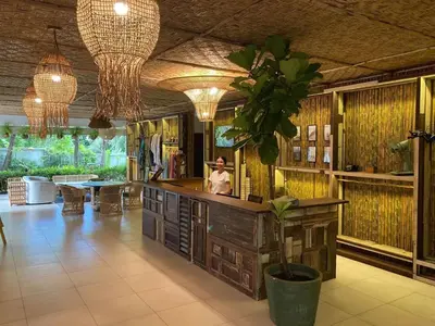 a man sitting at a counter in a room with a plant at Tropical Serenity - Elegant 1 Bedroom with Pool in Ban Saiyuan (1)