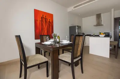a dining room with a table and chairs and a kitchen at Tropical Serenity - Elegant 1 Bedroom with Pool in Ban Saiyuan (1)