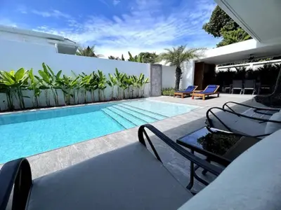 a swimming pool with chaise lounge chairs next to a house at Villa Anthoni - Cozy 3 bedrooms with pool in Rawai Beach