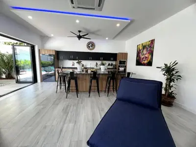 a living room with a blue couch and a kitchen at Villa Anthoni - Cozy 3 bedrooms with pool in Rawai Beach