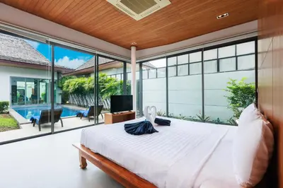 a bedroom with a large bed and a pool at Villa Coco - Classy Modern 2 Bedroom Pool Villa in Ban Saiyuan (1)