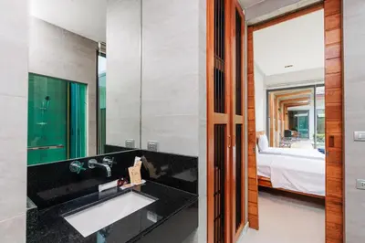 a bathroom with a sink and a bedroom with a bed at Villa Coco - Classy Modern 2 Bedroom Pool Villa in Ban Saiyuan (1)