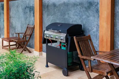 a grill sitting on a patio with two chairs at Villa Coco - Classy Modern 2 Bedroom Pool Villa in Ban Saiyuan (1)