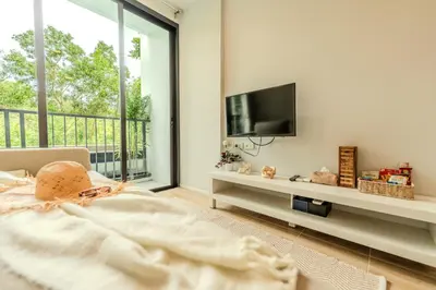 a bedroom with a bed and a tv and a balcony at ZcapeX2 94-17 by SilqStay in Bang Tao Beach