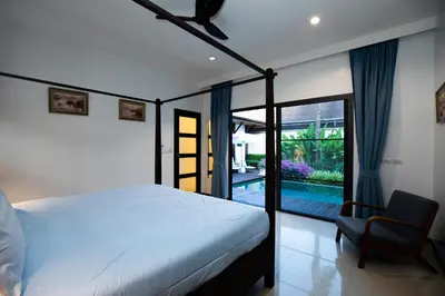 a bedroom with a bed and a chair and a pool at Villa Dinadi - Superb 2 Bedrooms Pool Villa in Rawai Beach