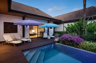 a house with a swimming pool and two umbrellas at Villa Dinadi - Superb 2 Bedrooms Pool Villa in Rawai Beach