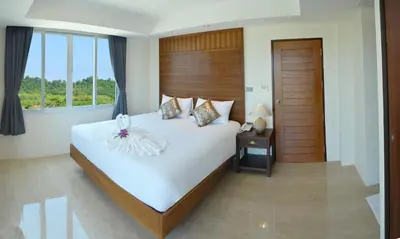 a bedroom with a large white bed and a window at David Residence in Nai Yang Beach