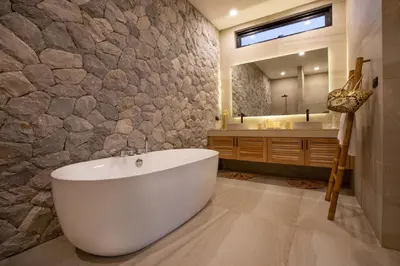 a bathroom with a tub and a stone wall at Nomad Villa - Elegant 3 Bedrooms Balinese Pool in Rawai Beach