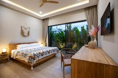 a bedroom with a bed and a table and a window at Nomad Villa - Elegant 3 Bedrooms Balinese Pool in Rawai Beach