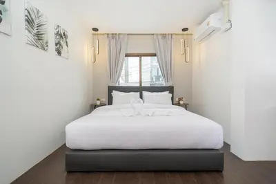 a bedroom with a white bed and a window at 7BR Patong pool villa in Patong Beach