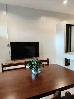 a living room with a wooden table with a vase of flowers at Le Wadee Residence in Bang Tao Beach