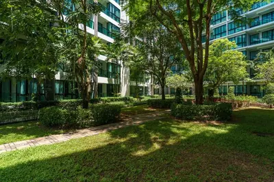 a park in front of a building with trees at New 1 Bdr Royal Lee Nayang beach in Ban Bo Han
