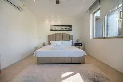 a bedroom with a bed and a large window at Botanica 4 BR Villa Layan Beach in Ban Phru Champa