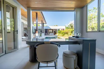 a kitchen with a black counter and a chair at Botanica 4 BR Villa Layan Beach in Ban Phru Champa