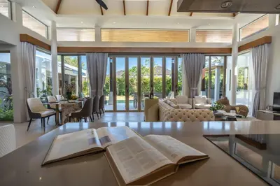 an open book on a table in a living room at Botanica 4 BR Villa Layan Beach in Ban Phru Champa