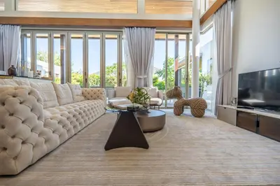 a living room with a large couch and a television at Botanica 4 BR Villa Layan Beach in Ban Phru Champa