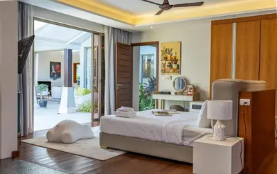 a bedroom with a bed and a sliding glass door at Botanica 4 BR Villa Layan Beach in Ban Phru Champa
