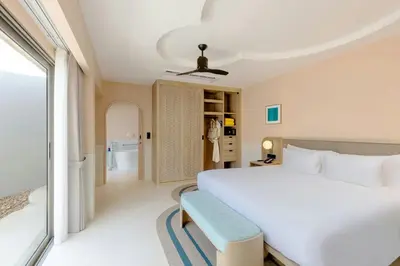 a bedroom with a white bed and a blue bench at Centara Karon Villas Phuket in Karon Beach