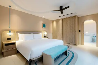 a bedroom with a large white bed and a blue stool at Centara Karon Villas Phuket in Karon Beach