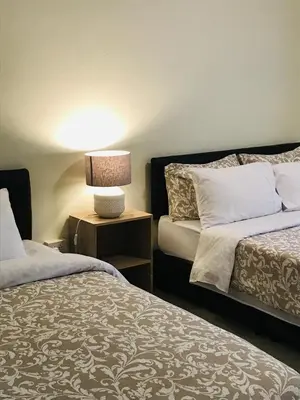 a bedroom with two beds and a table with a lamp at Green View suite with private bathroom and kitchen in Ban Phlu Yai