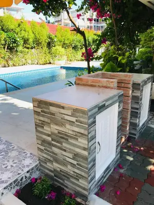 a stone wall with a white door next to a pool at Green View suite with private bathroom and kitchen in Ban Phlu Yai