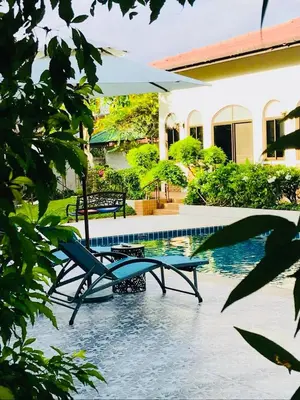 a swimming pool with two chairs next to a house at Green View suite with private bathroom and kitchen in Ban Phlu Yai