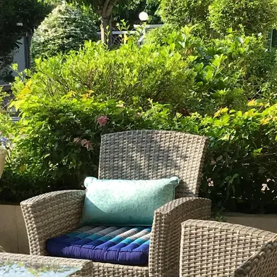 a wicker chair with a blue pillow on it at Green View suite with private bathroom and kitchen in Ban Phlu Yai