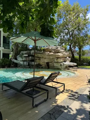two chairs and an umbrella next to a swimming pool at Pool Access Beachfront Studio in Phuket Town