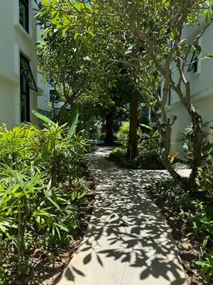 a walkway with trees and plants next to a building at Pool Access Beachfront Studio in Phuket Town
