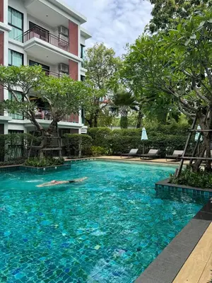 a person swimming in a swimming pool in front of a building at Pool Access Beachfront Studio in Phuket Town