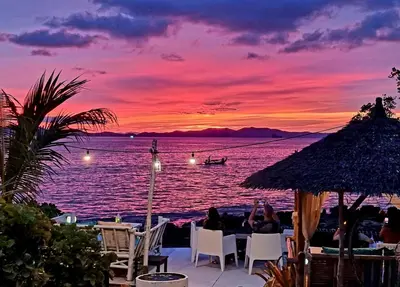 a group of people sitting at a table with a sunset at Krabi Sea view, Lilly Beach Room Balibar in Krabi town