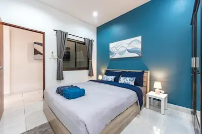 a bedroom with a large bed with a blue wall at The Coastal Haven Holiday Home, Karon Beach in Karon Beach