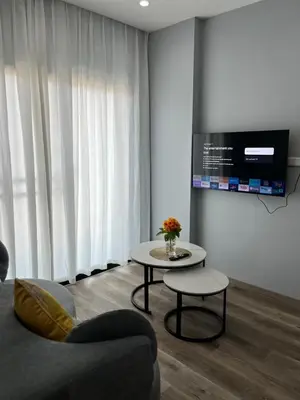 a living room with a couch and a table and a tv at UPMOON Hotel Chalong Phuket in Ban Suan