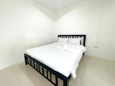 a white bed with a black frame and white sheets at Patong Canal Villa 102 in Patong Beach